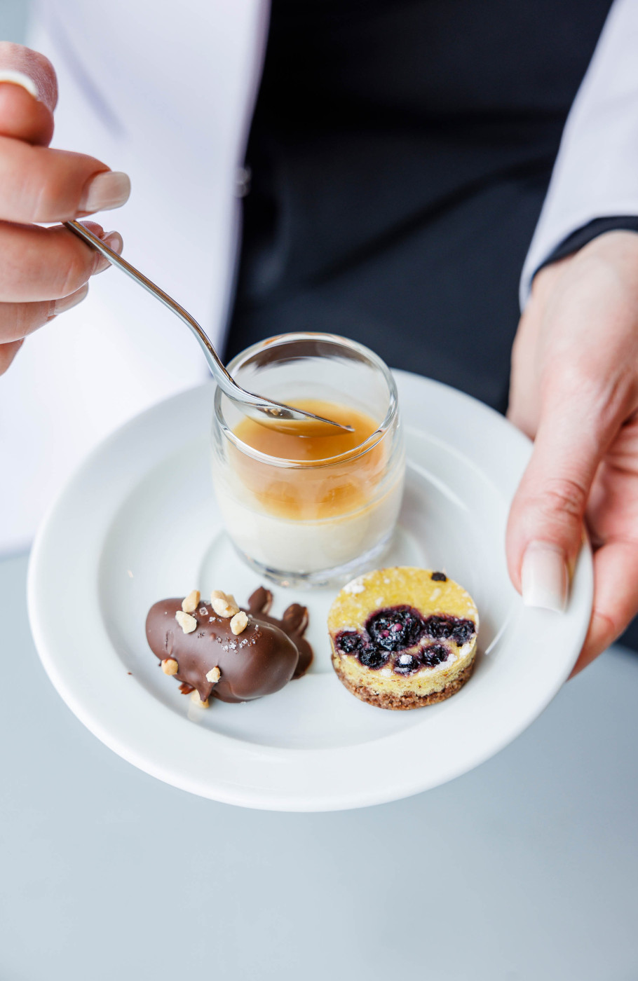 Person hält Teller mit drei kleinen Desserts