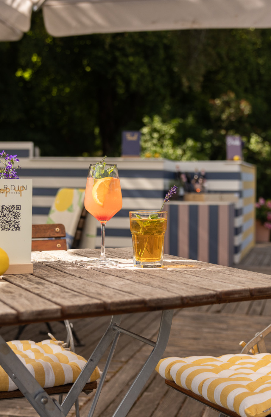 Terrassenszene mit weissem Sonnenschirm, Holztischen und Lavendelpflanzen auf den Tischen