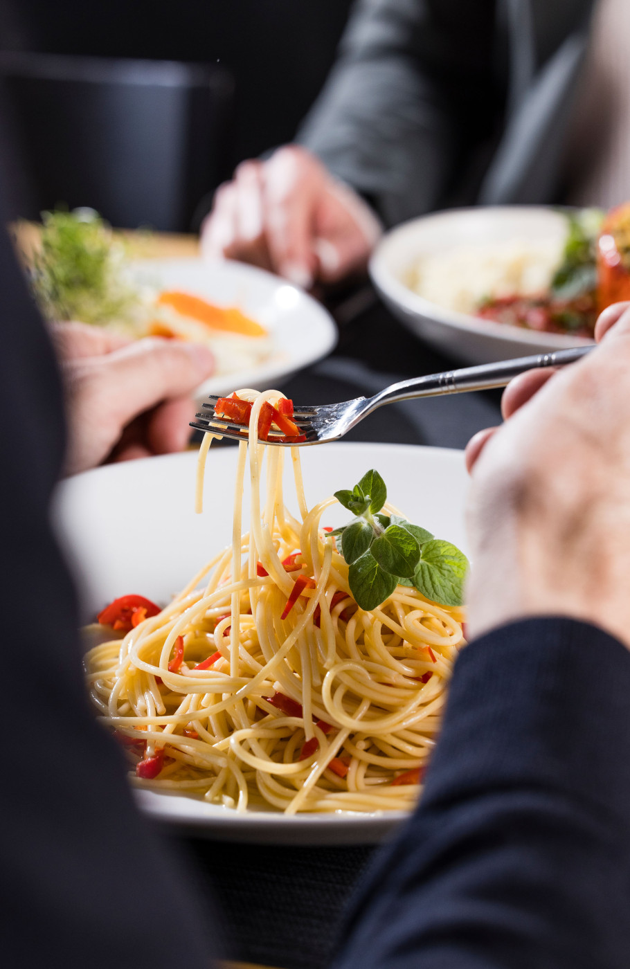 Spaghetti mit frischen Kräutern werden gerade auf Gabel geladen, gegenüber italienisches Gericht