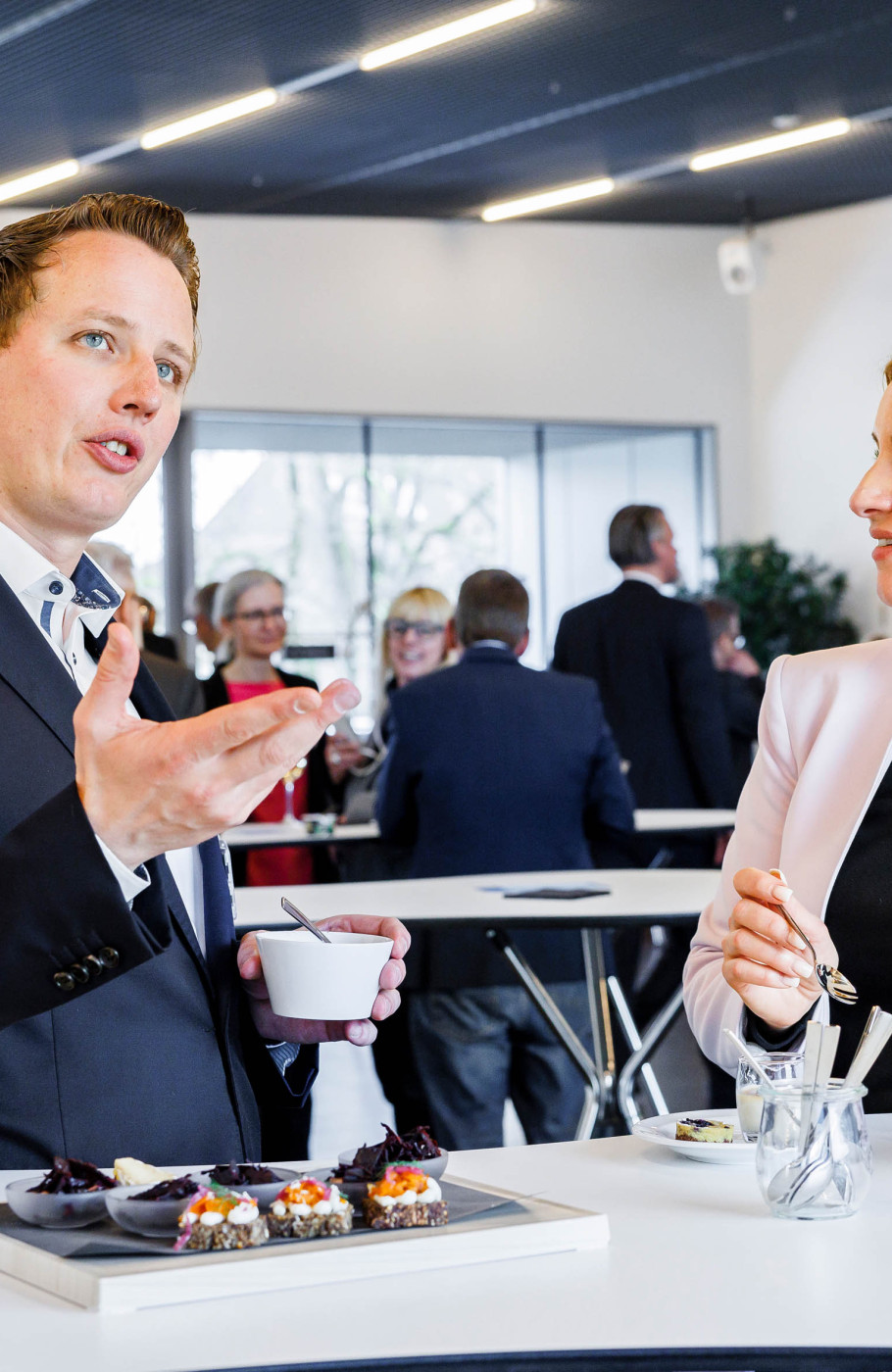 Ein elegant gekleiderter Mann unterhält sich mit einer Dame an einem Event