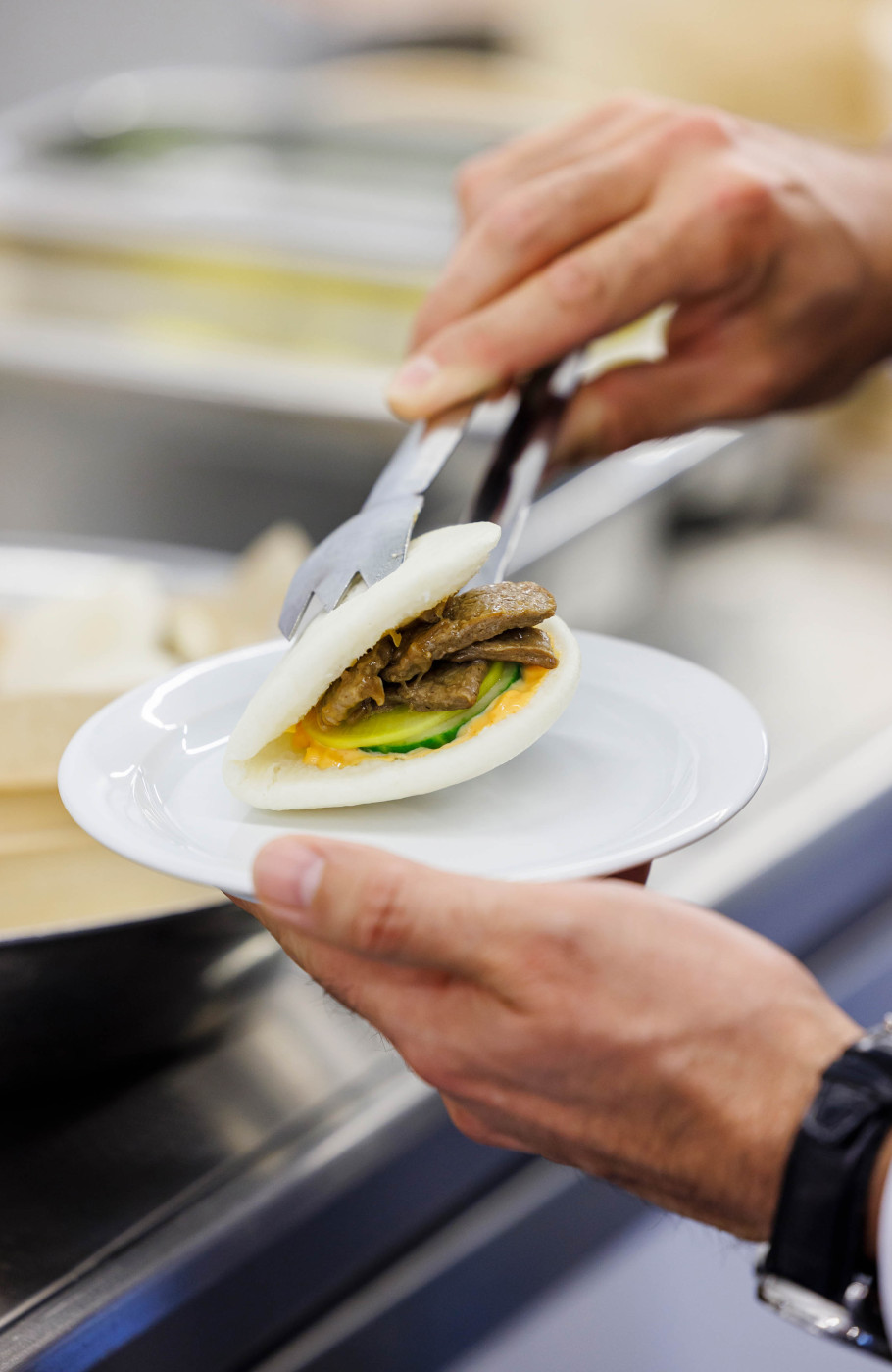 Gefülltes, veganes Bun wird von einem Mann auf einen Teller gesetzt