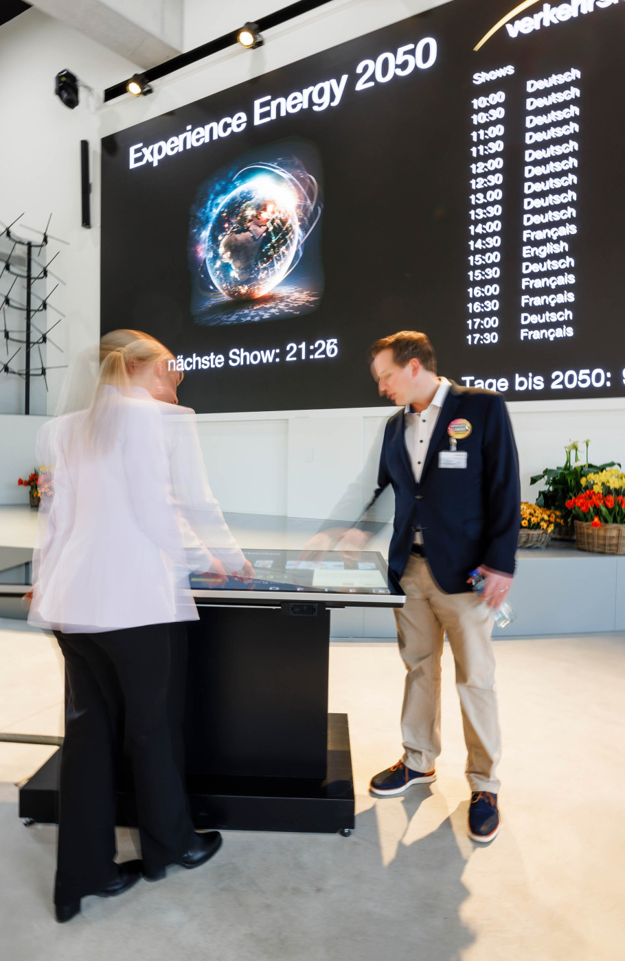 Leinwand mit Experience Energy Daten davor zwei Personen an einem digitalen Screen