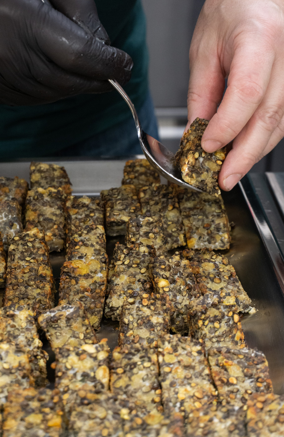 Vegetarische Quadrate werden von Hand auf einem Blech angerichtet