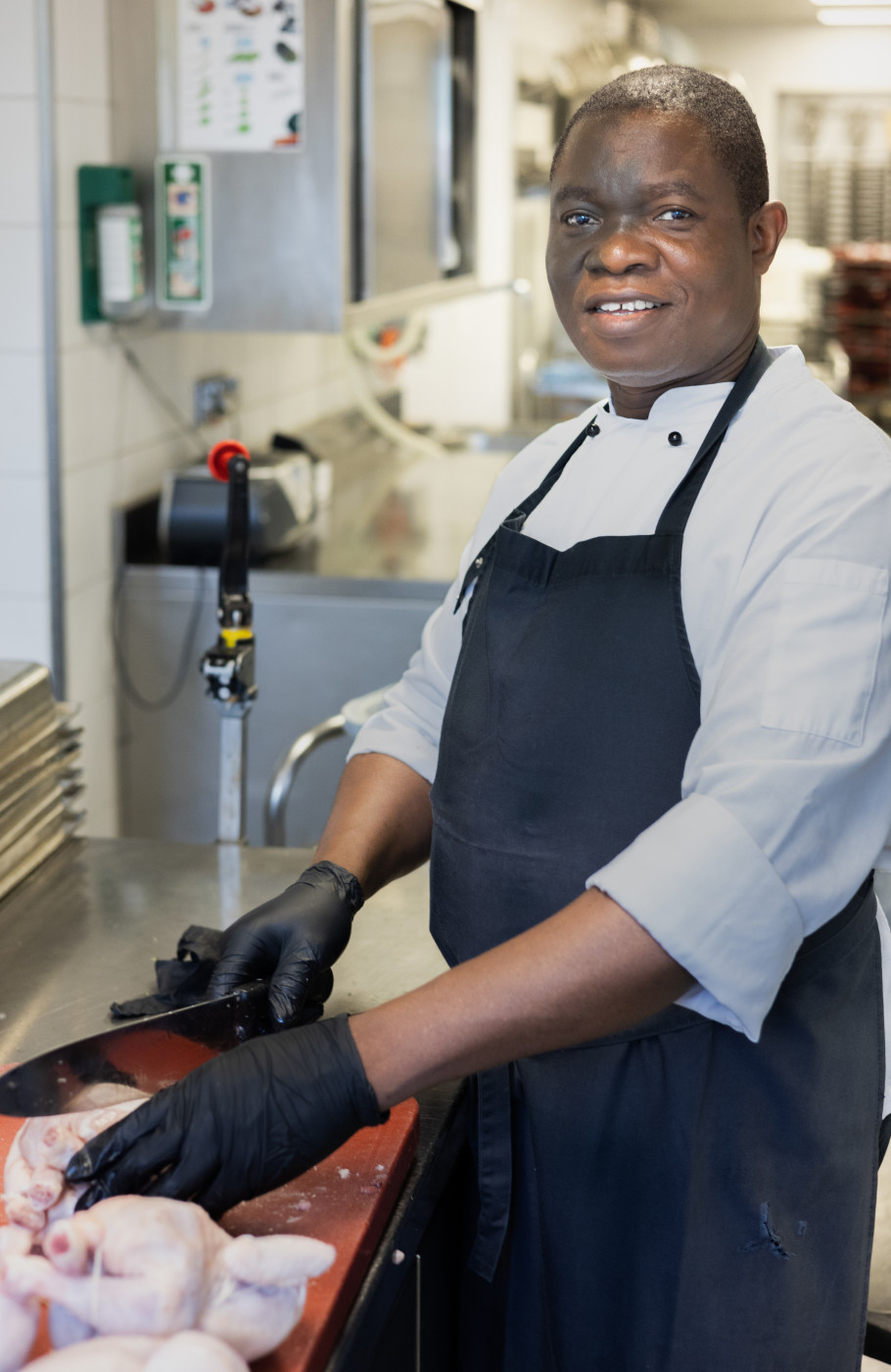 Mann in Kochuniform bereitet Hühnchen in Gastronomieküche zu