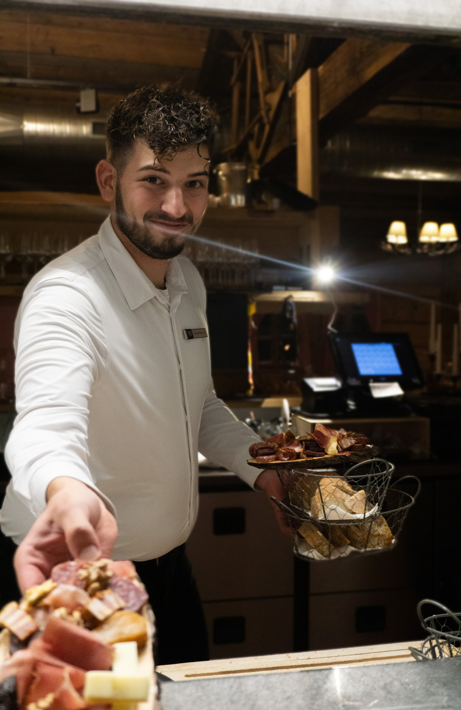 Männliche Servicefachkraft greift nach einer kalten Platte, eine zweite hält sie in der anderen Hand