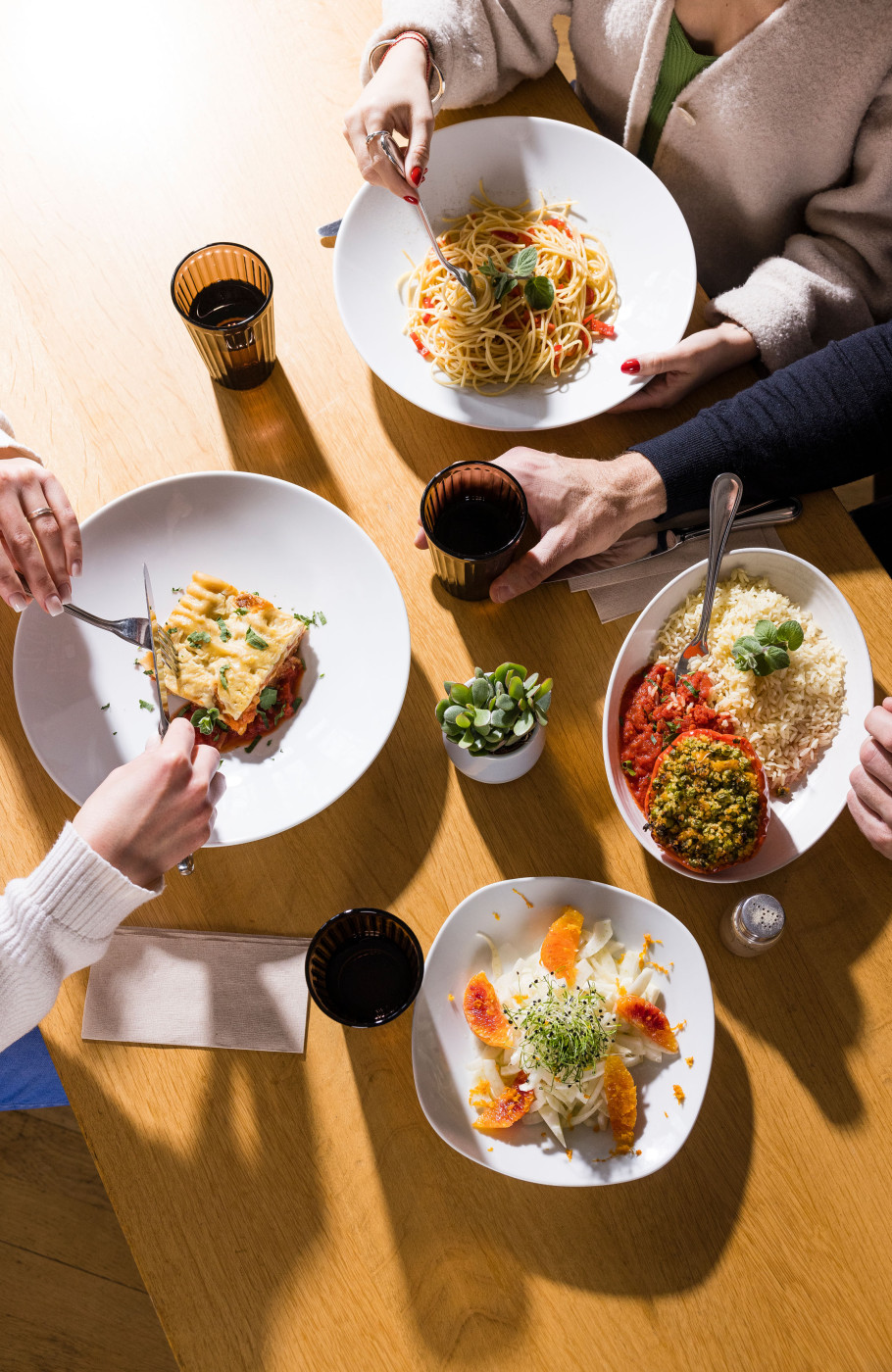 Tisch mit vier Gerichten und Menschen beim Essen