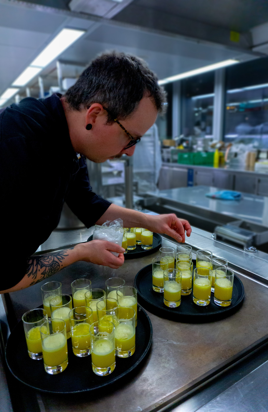 Koch in schwarzer Uniform würzt Gläser mit Ananassaft