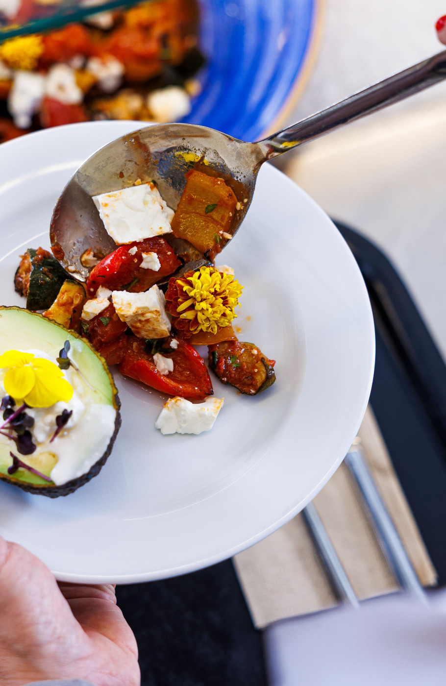 Teller, der am Buffet beladen wird mit Gemüse und Avocado