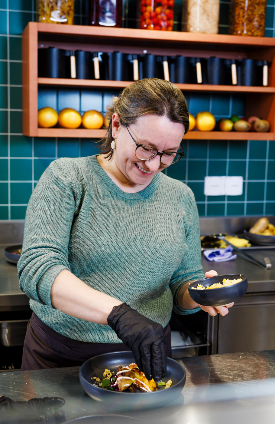 Junge Frau bereitet ein Gericht in einer Gastronomieküche