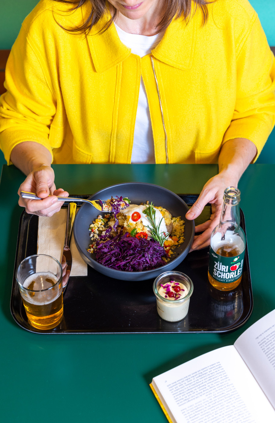 Frau in gelber Jacke isst ihren Lunch