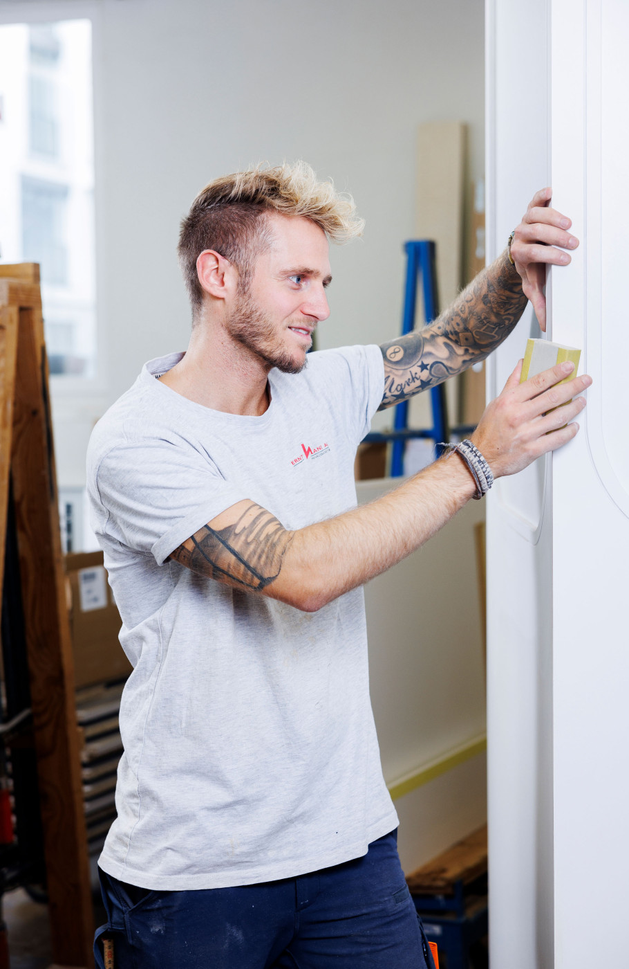 Ein junger Mann schleift eine Holztüre von Hand