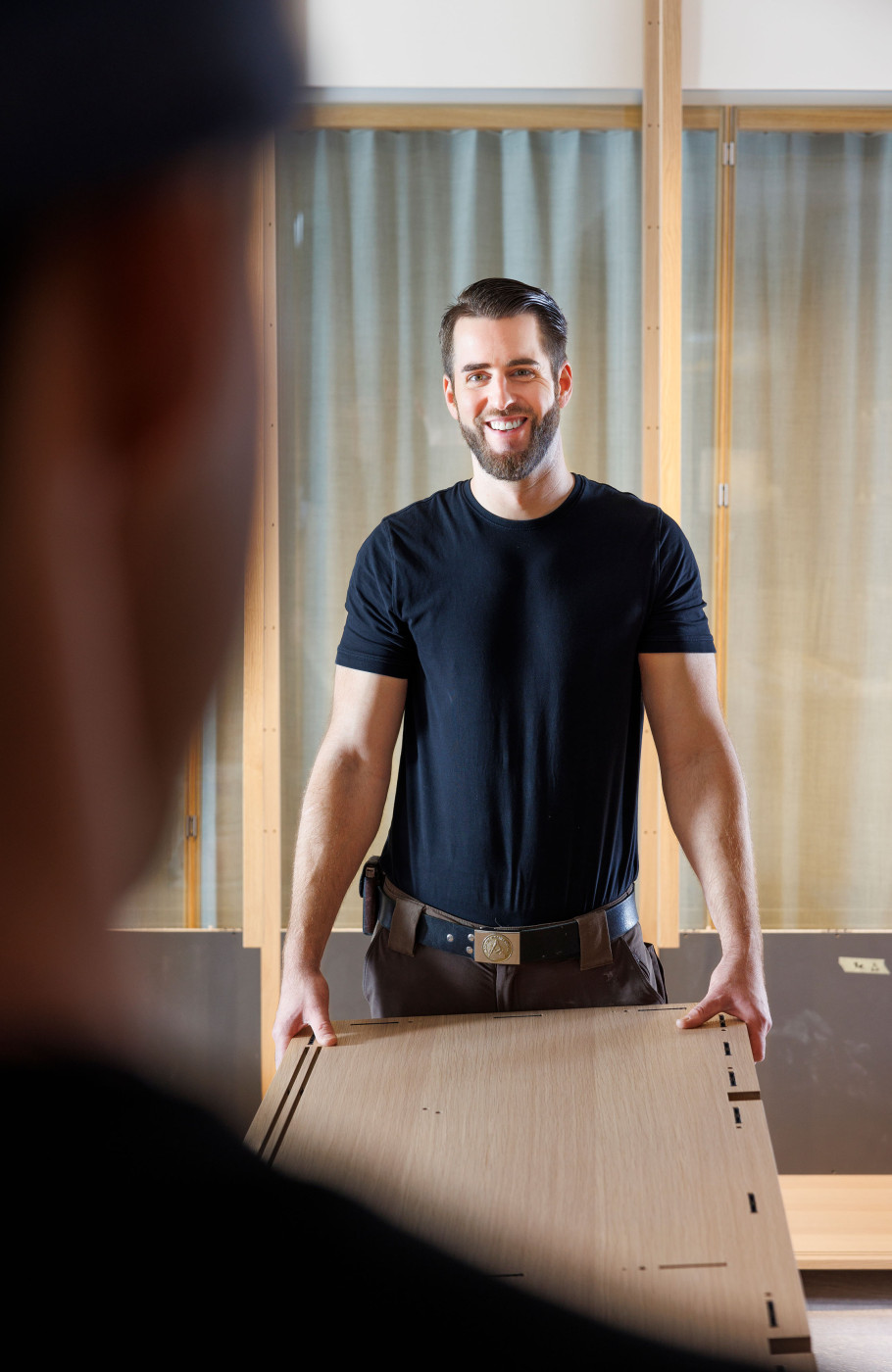 Zwei Männer tragen eine lange Holzplatte