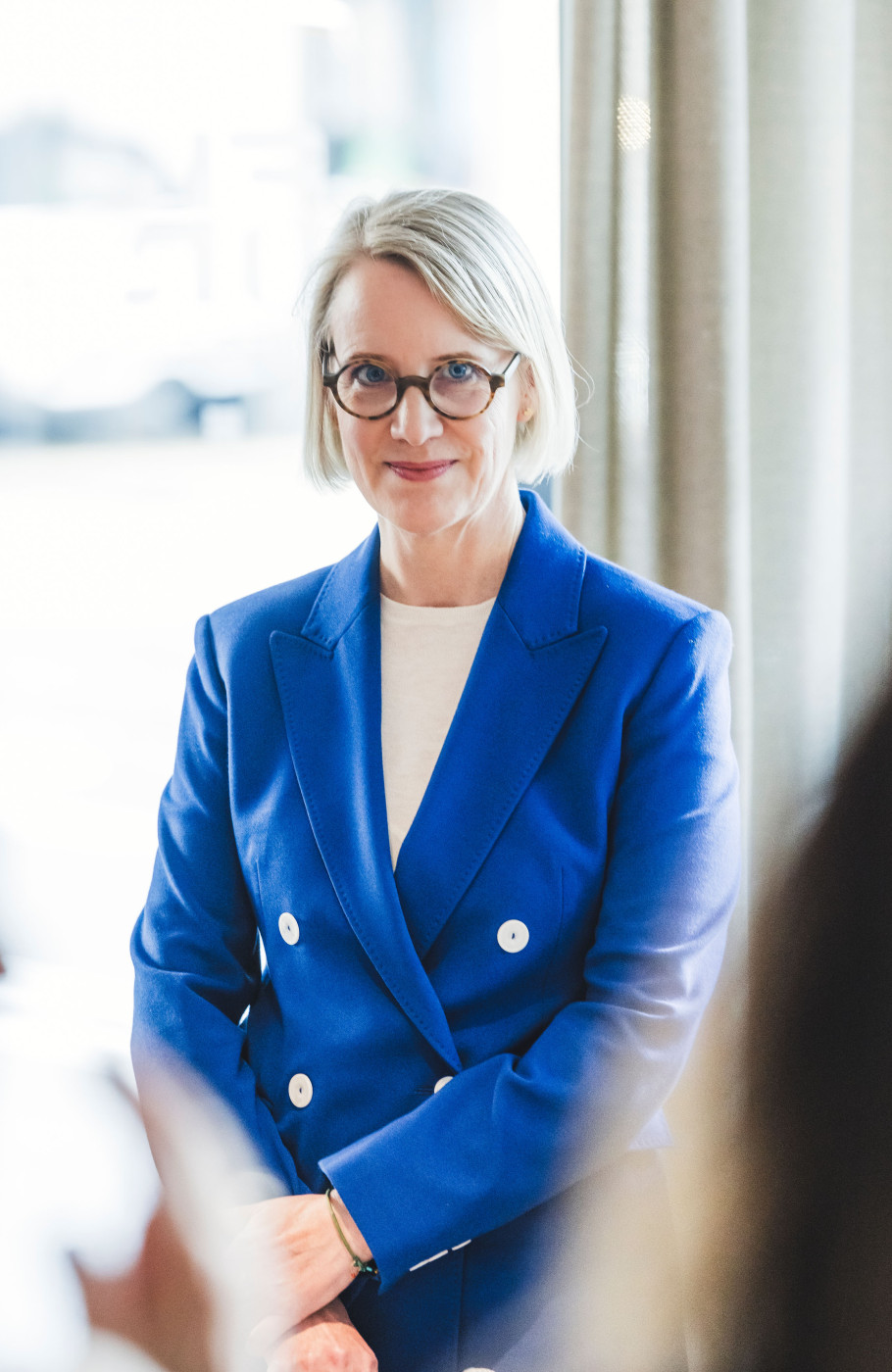 Frau in blauem Anzug mit Brille