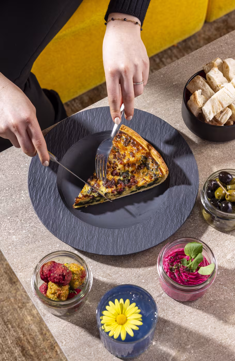 Weibliche Hände schneiden eine Quiche