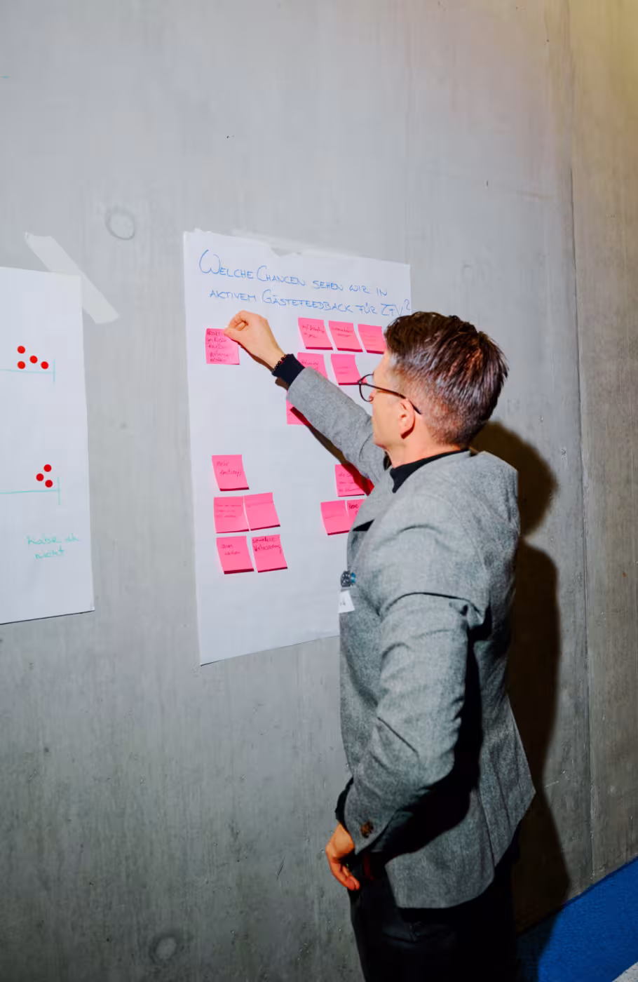 Ein Mann klebt Postits auf ein an der Wand hängendes Blatt