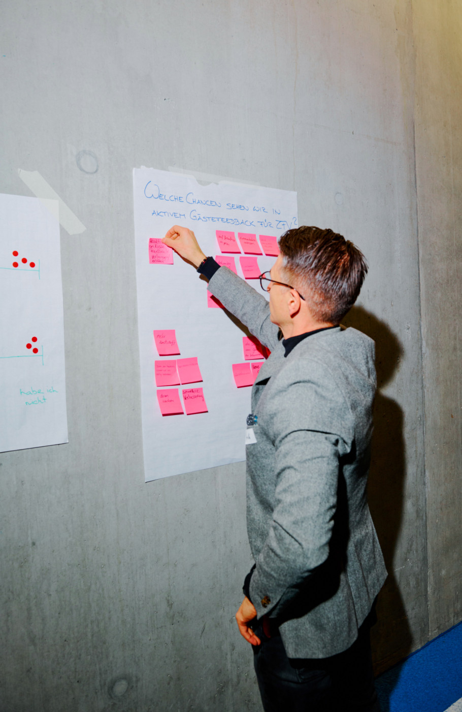 Ein Mann klebt Postits auf ein an der Wand hängendes Blatt