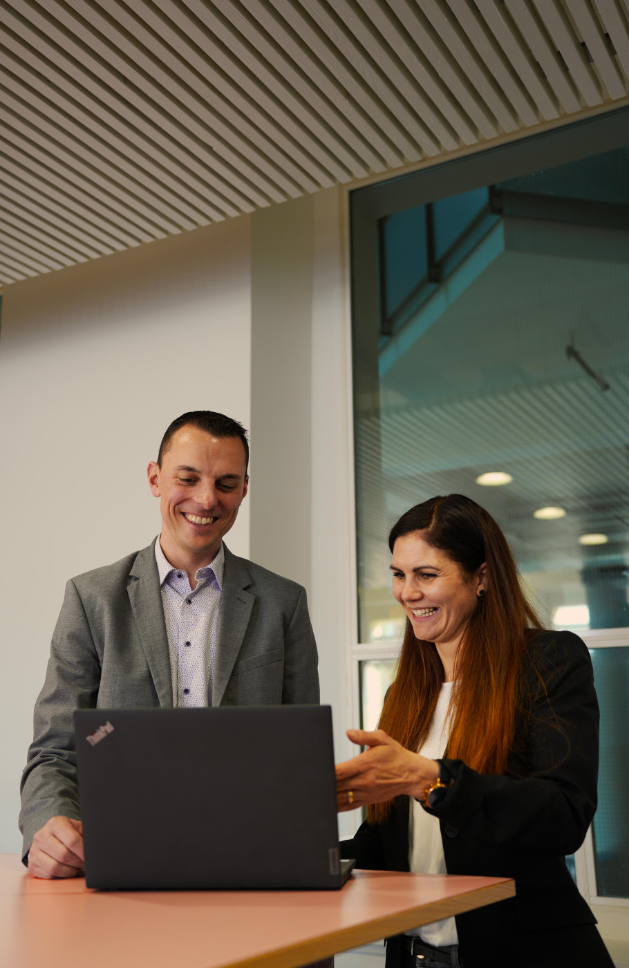 Zwei Personen tauschen sich lachend vor einem Laptop aus