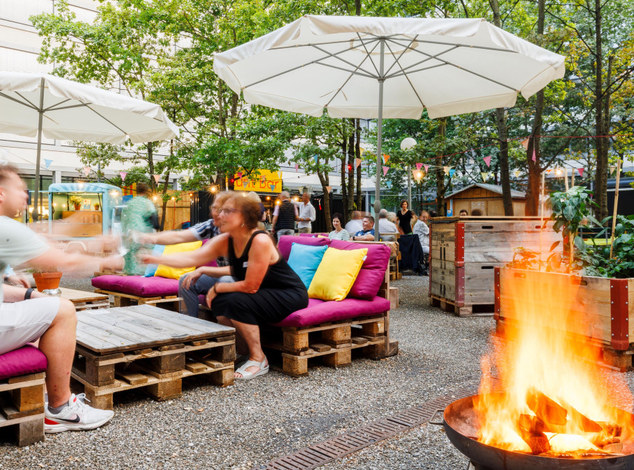 Personen sitzen auf Lounges und essen im Pünt Sommergarten