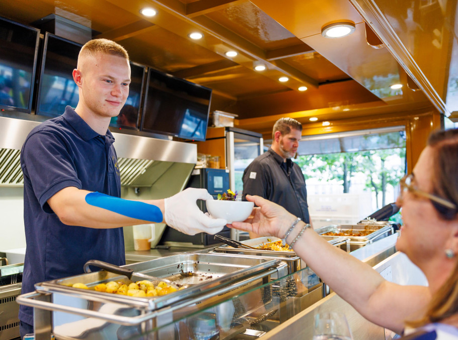 Servicefachangestellter bedient einen Gast beim Foodtruck des Pünt Sommergartens