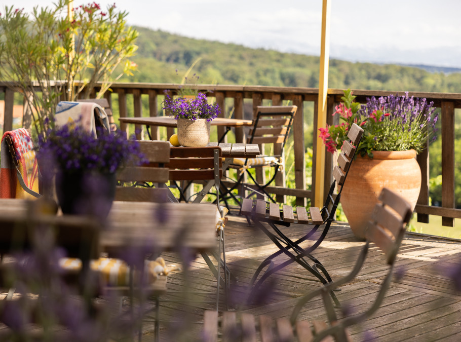 Terrasse mit Aussicht auf gründe Landschaften, Holzstühle sowie Lavendelpflanzen im Vordergrund