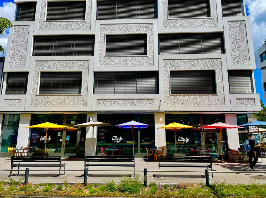 Promenadenterrasse mit bunten Terrassenschirmen vor dem grauen Gebäude des Restaurant Lilly Jo