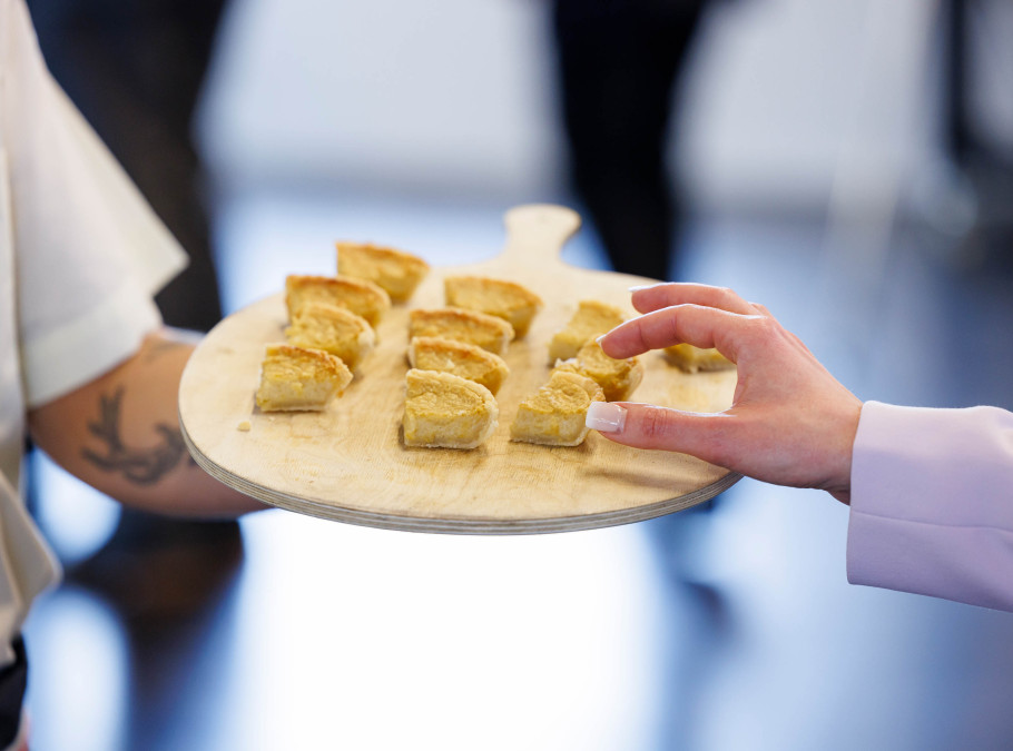 Vegane Chäseküchlein geviertelt auf einem Holzbrett werden von einem Servicemitarbeiter gereicht