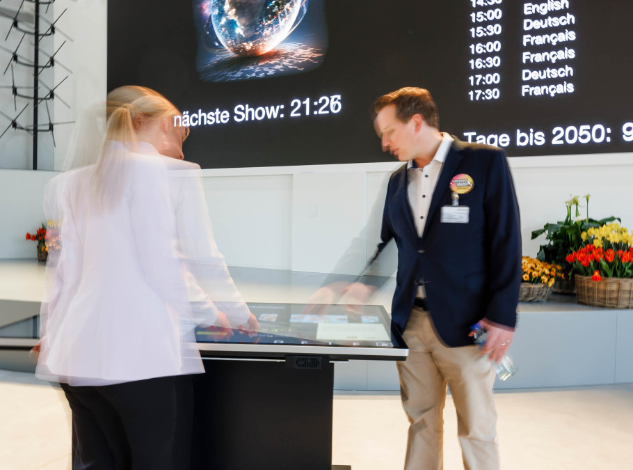 Leinwand mit Experience Energy Daten davor zwei Personen an einem digitalen Screen
