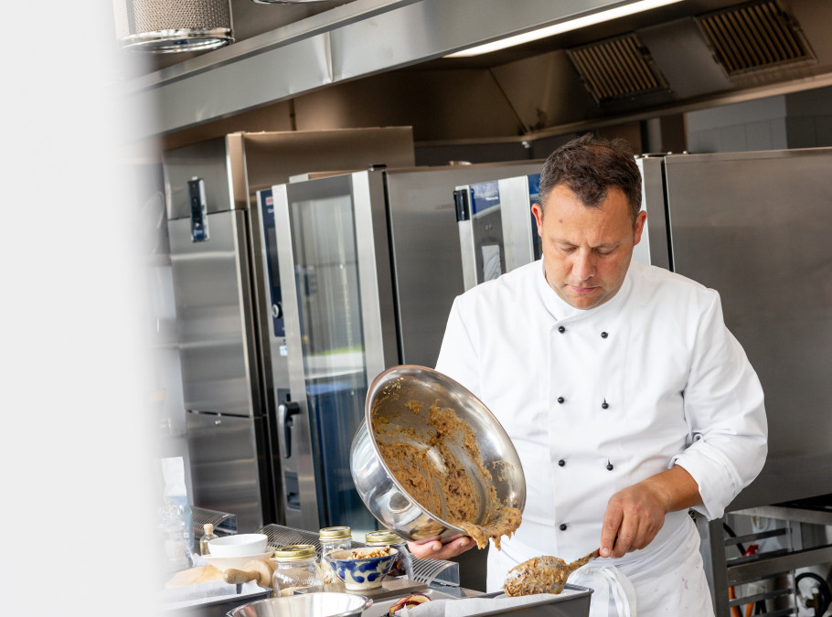 Mann in Kochjacke bereitet Essen in einer Gastronomieküche zu