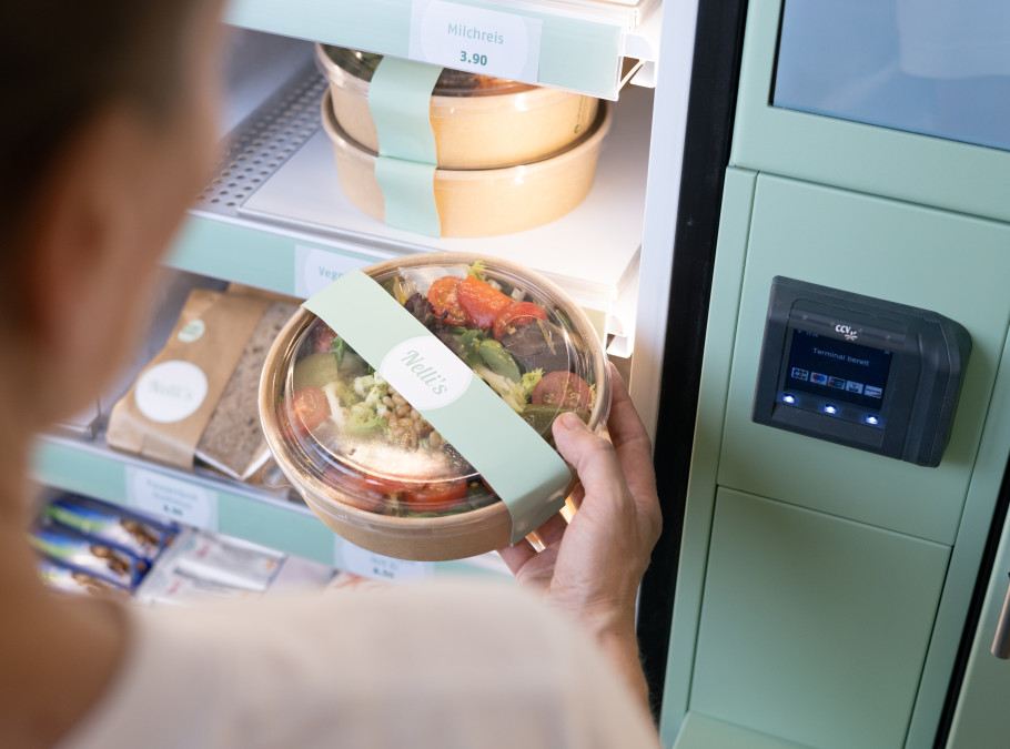 Frau zieht aus einem Smartfridge einen verpackten Salat