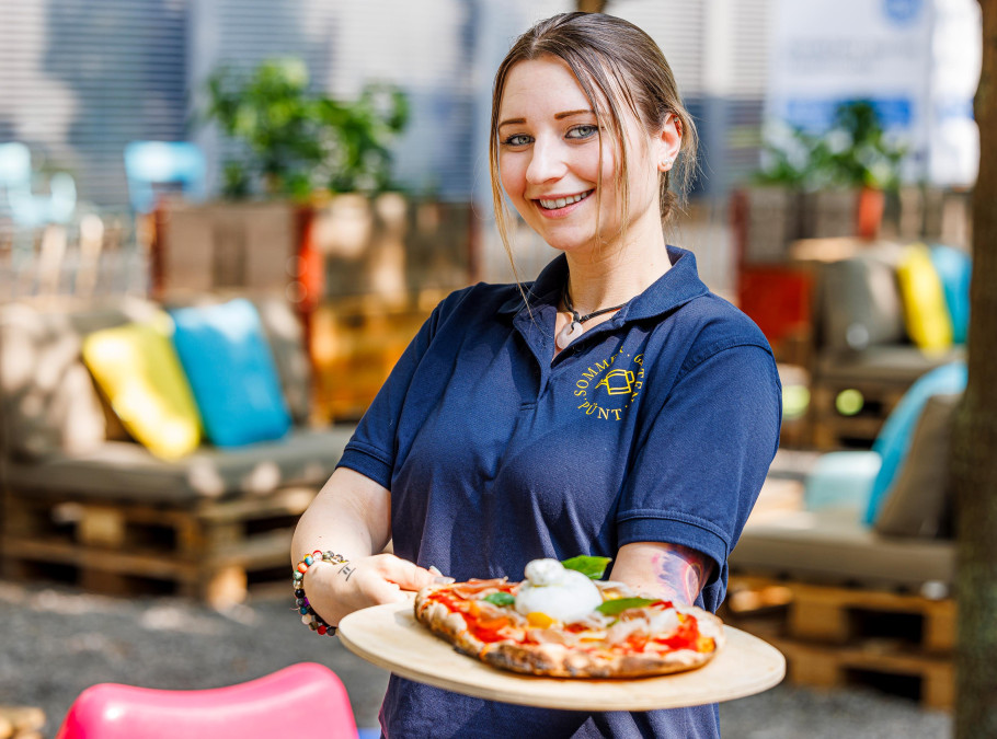 junge Frau in blauem T-Shirt hält Platte mit Pizza