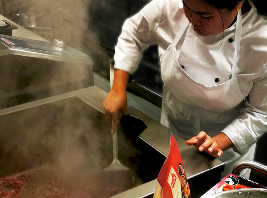 Junge Köchin bereitet ein Essen in einer Gastronomieküche zu