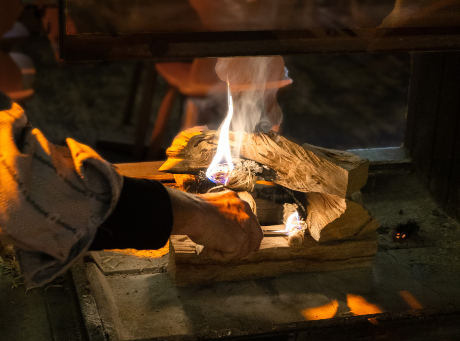 Chimenéefeuer mit einer Hand, welche dieses anzündet