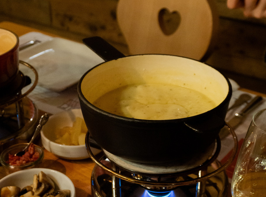 Fonduepfanne mit geschmolzenem Käse auf einem gedeckten Tisch