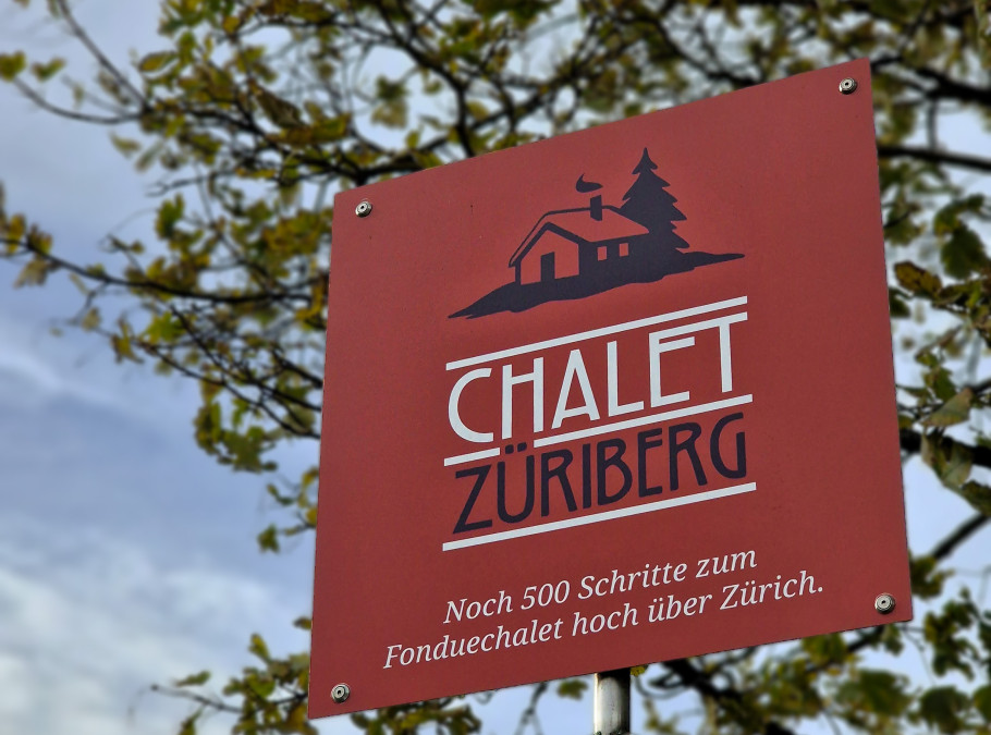 Rotes Schild vor einem blauen Himmel mit der Aufschrift Chalet Zürichberg