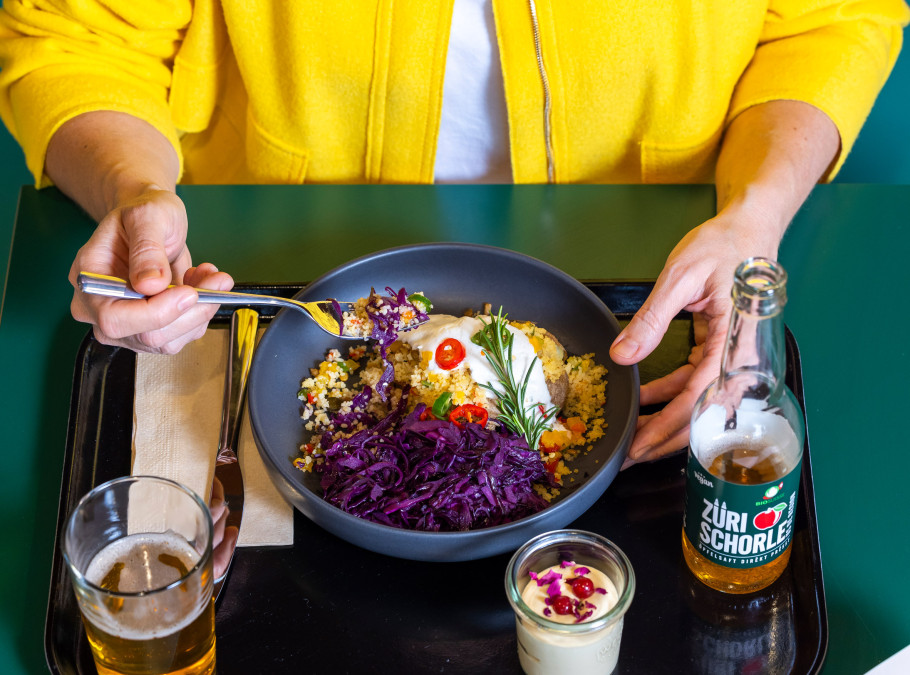 Frau in gelber Jacke isst ihren Lunch