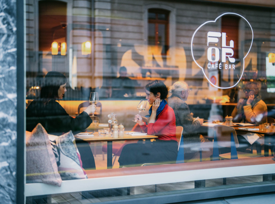 Glasfront eines Restaurants mit Logo, durch das Glas sind die Gäste im Restaurant zu sehen