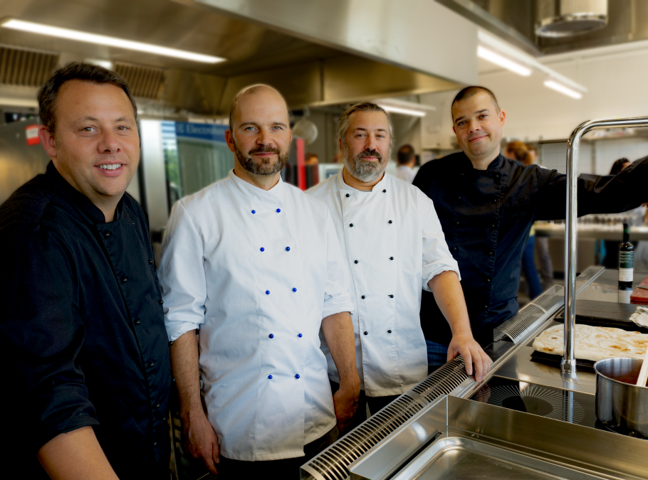 Vier Köche in Uniform in einer Gastronomieküche