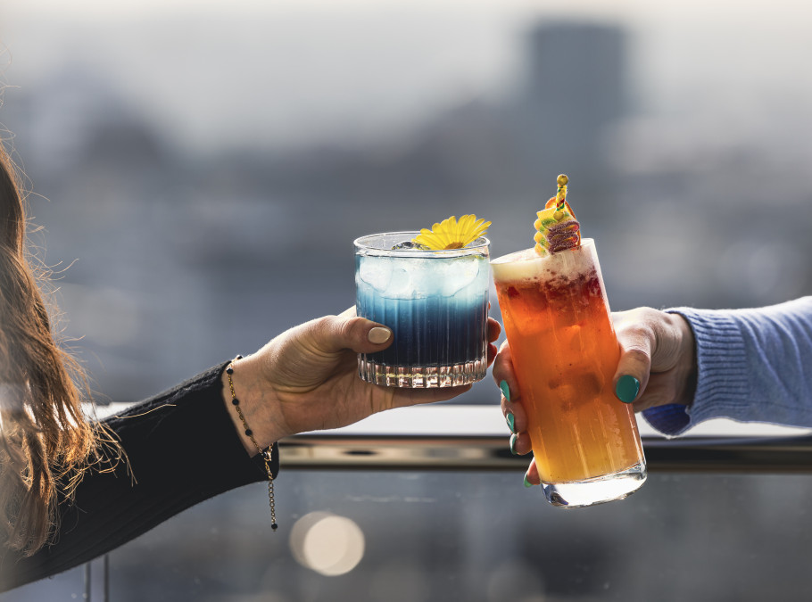 Zwei weibliche Hände stossen mit Cocktails an