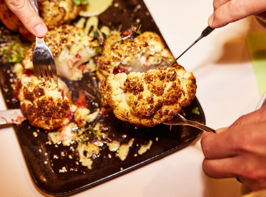 Blumenkohl auf einer Platte mit Menschen, die teilen