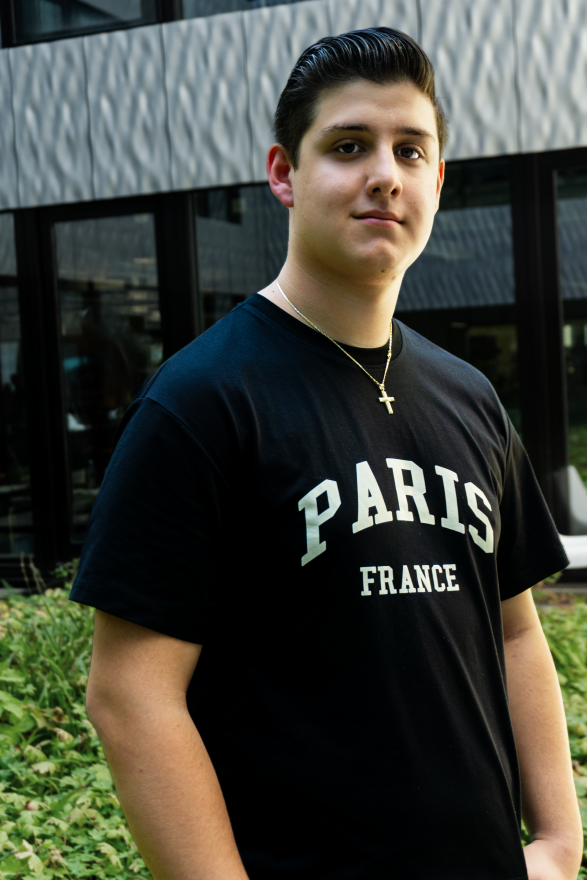 junger Mann im schwarzen T-Shirt steht vor Fensterfront