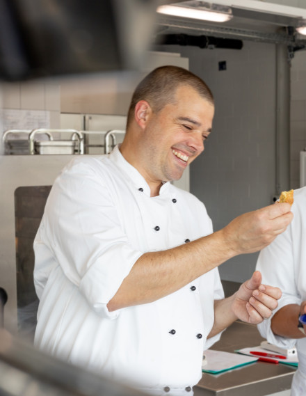 Mann in Kochjacke steht in einer Gastronomieküche