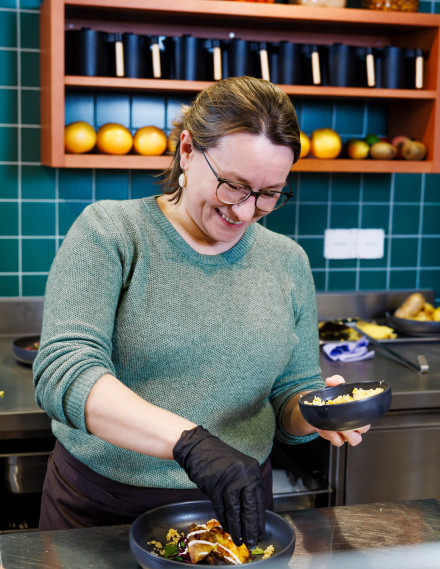 Junge Frau bereitet ein Gericht in einer Gastronomieküche