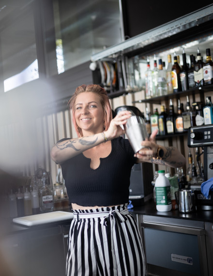 Junge Frau mit pinken Haaren shaket einen Cocktail