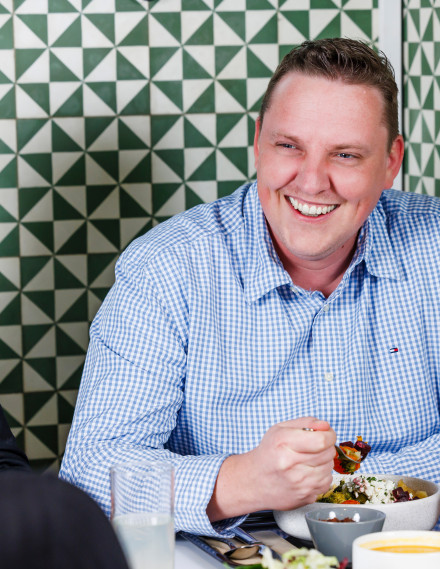 Mann beim Essen an einem Tisch lächelt