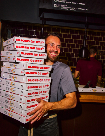 Mann in einem Restaurant hält einen Stapel Pizzakartons