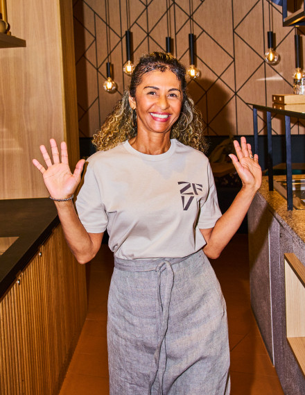 Frau in einem Restaurant läuft lächelnd auf die Kamera zu
