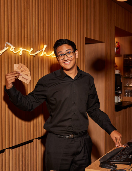 Junger Mann in schwarzem Hemd steht an einer Hotelreception