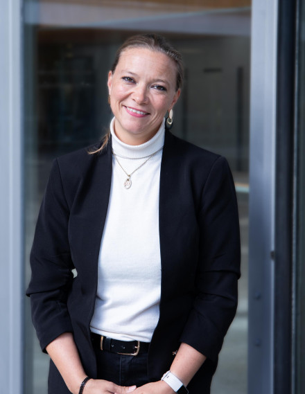 Frau steht lächelnd vor der Kamera