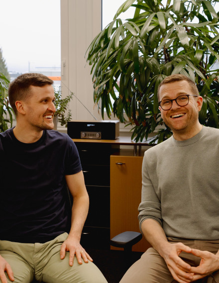 Zwei Männer lachen in die Kamera