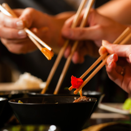 Personen essen asiatische Gerichte mit Stäbchen